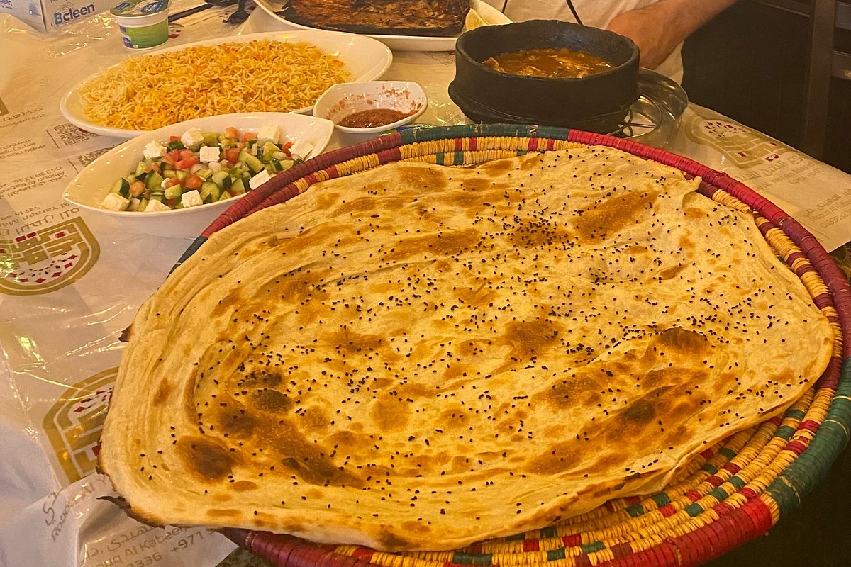 A shared Al Yemen Mandi spread — malawah bread in a woven basket with saffron rice, salad and sauces